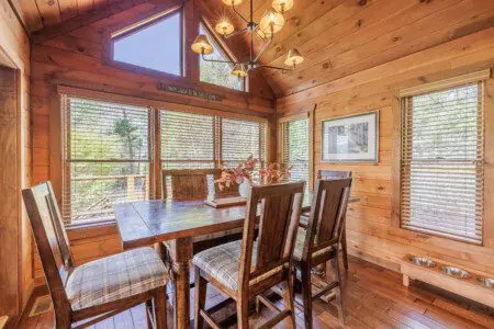 Above the Clouds cabin dining area with wood table and vaulted ceiling in Blue Ridge Georgia