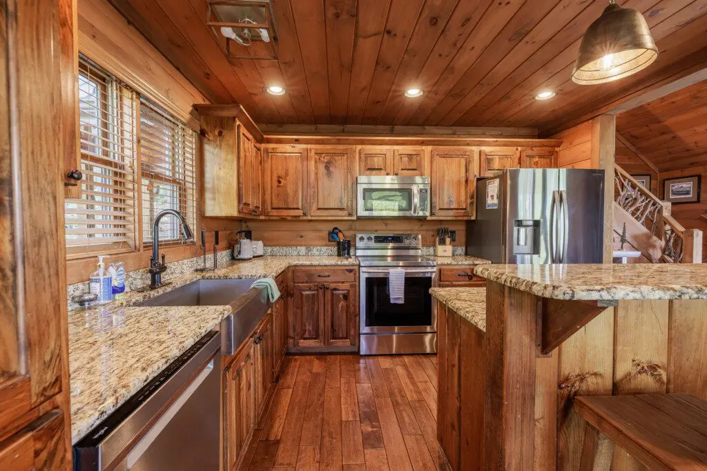 Above the Clouds cabin kitchen with farmhouse sink granite counters and stainless appliances in Blue Ridge Georgia