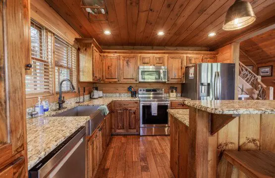 Above the Clouds cabin kitchen with farmhouse sink granite counters and stainless appliances in Blue Ridge Georgia