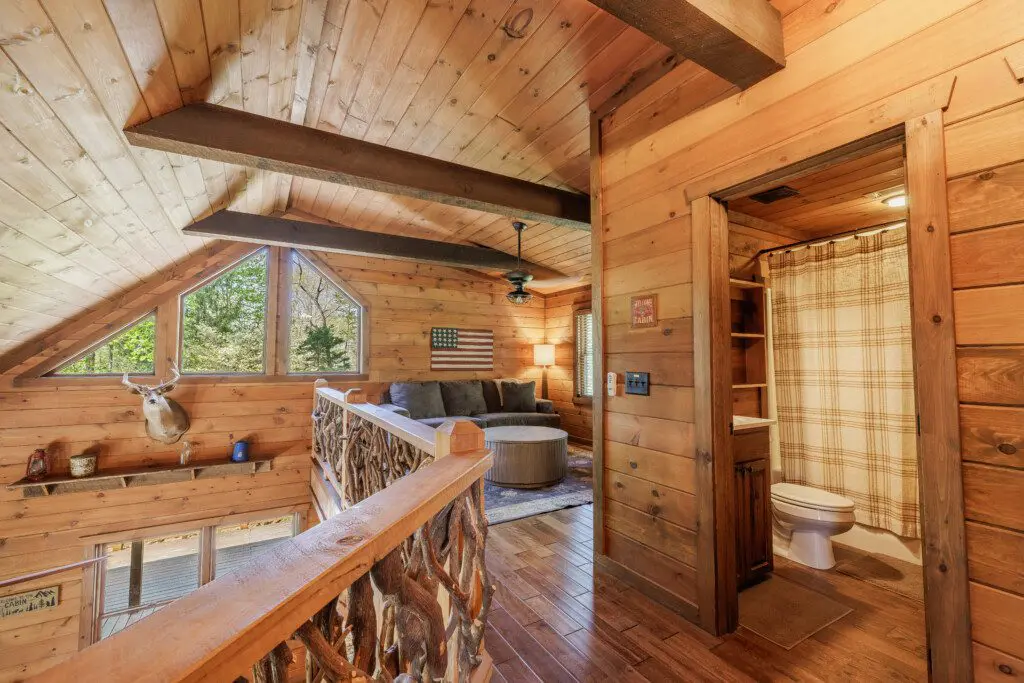 Above the Clouds cabin loft lounge area with antler railing and private bathroom in Blue Ridge Georgia