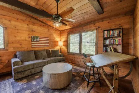 Above the Clouds cabin loft sitting room with drafting table bookshelf and Americana decor in Blue Ridge Georgia