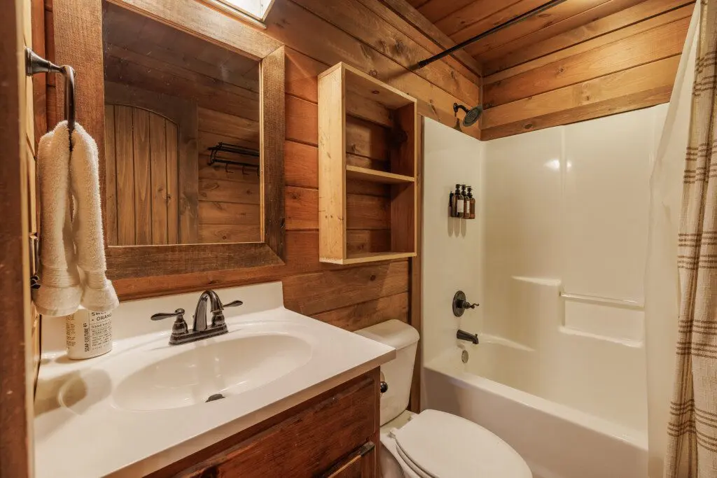 Above the Clouds cabin loft bathroom with tub shower combo and rustic wood vanity in Blue Ridge Georgia