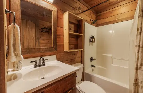 Above the Clouds cabin loft bathroom with tub shower combo and rustic wood vanity in Blue Ridge Georgia