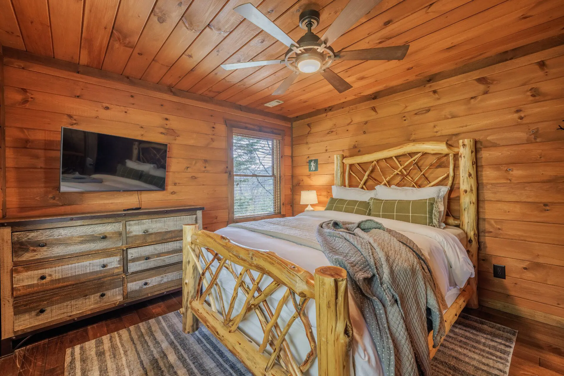 Above the Clouds cabin upstairs bedroom with log twig bed frame and mounted TV in Blue Ridge Georgia