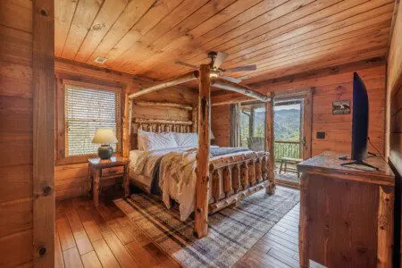 Above the Clouds cabin bedroom with log four poster bed and private deck mountain view in Blue Ridge Georgia