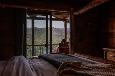 Above the Clouds cabin bedroom view of guest sitting on private deck overlooking North Georgia mountains in Blue Ridge Georgia