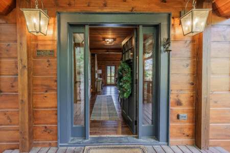 Above the Clouds cabin front entrance with sage green door and lantern lighting in Blue Ridge Georgia