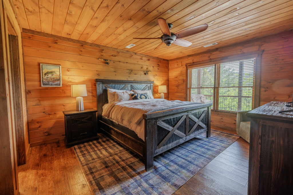 Above the Clouds cabin lower level bedroom with rustic barnwood bed frame and deck access in Blue Ridge Georgia