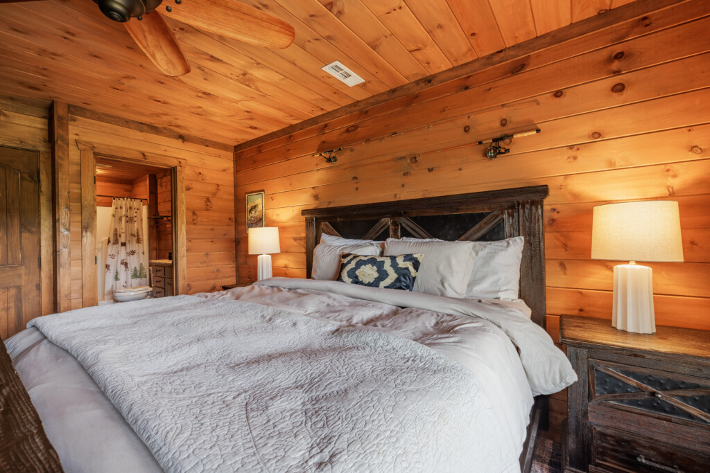 Above the Clouds cabin lower level bedroom with barnwood headboard and connected bathroom in Blue Ridge Georgia