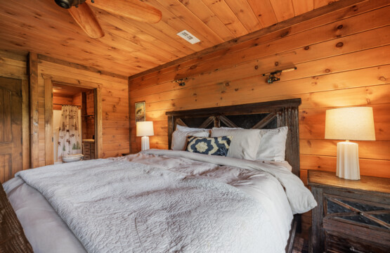 Above the Clouds cabin lower level bedroom with barnwood headboard and connected bathroom in Blue Ridge Georgia